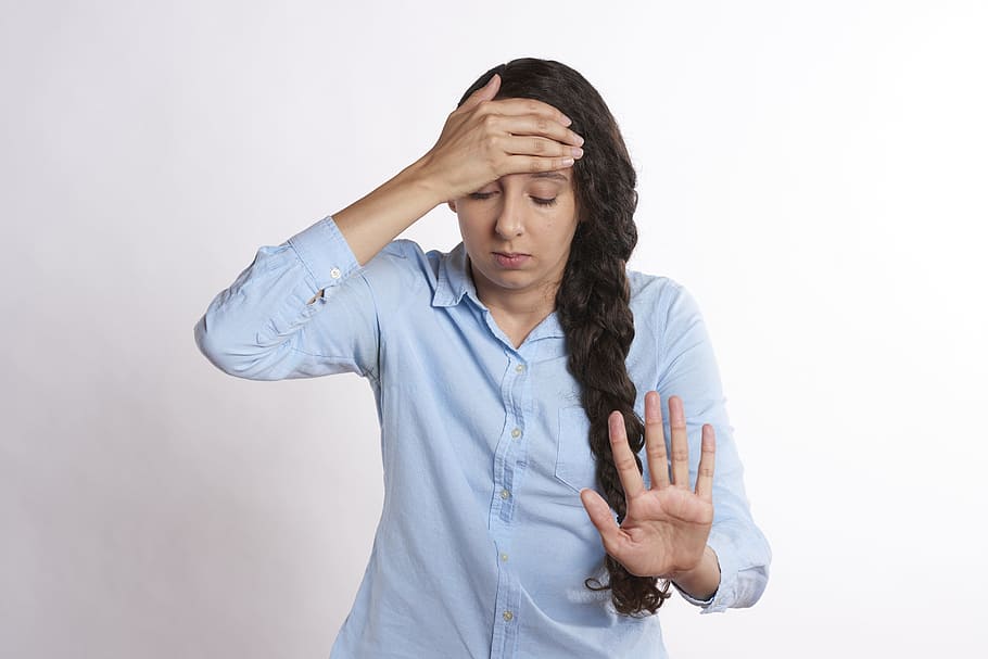 A woman, dressed in a blue blouse, feeling the physical and psychological impact of stress.