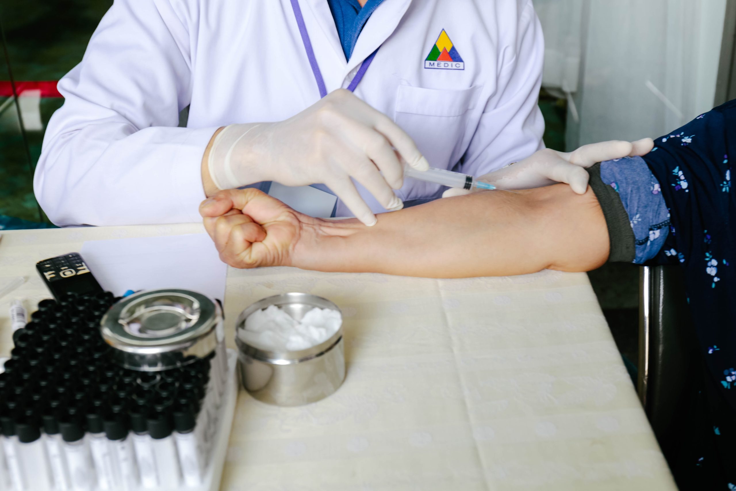 A doctor in a white coat administering a shot to someone’s forearm.